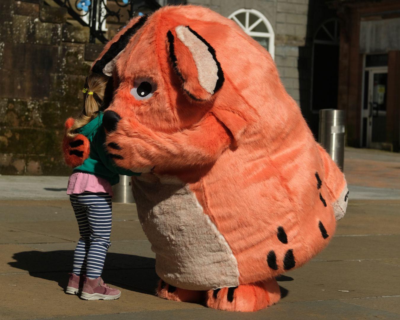 Big DoG meeting a young fan. The orange mascot is giving a child a hug.