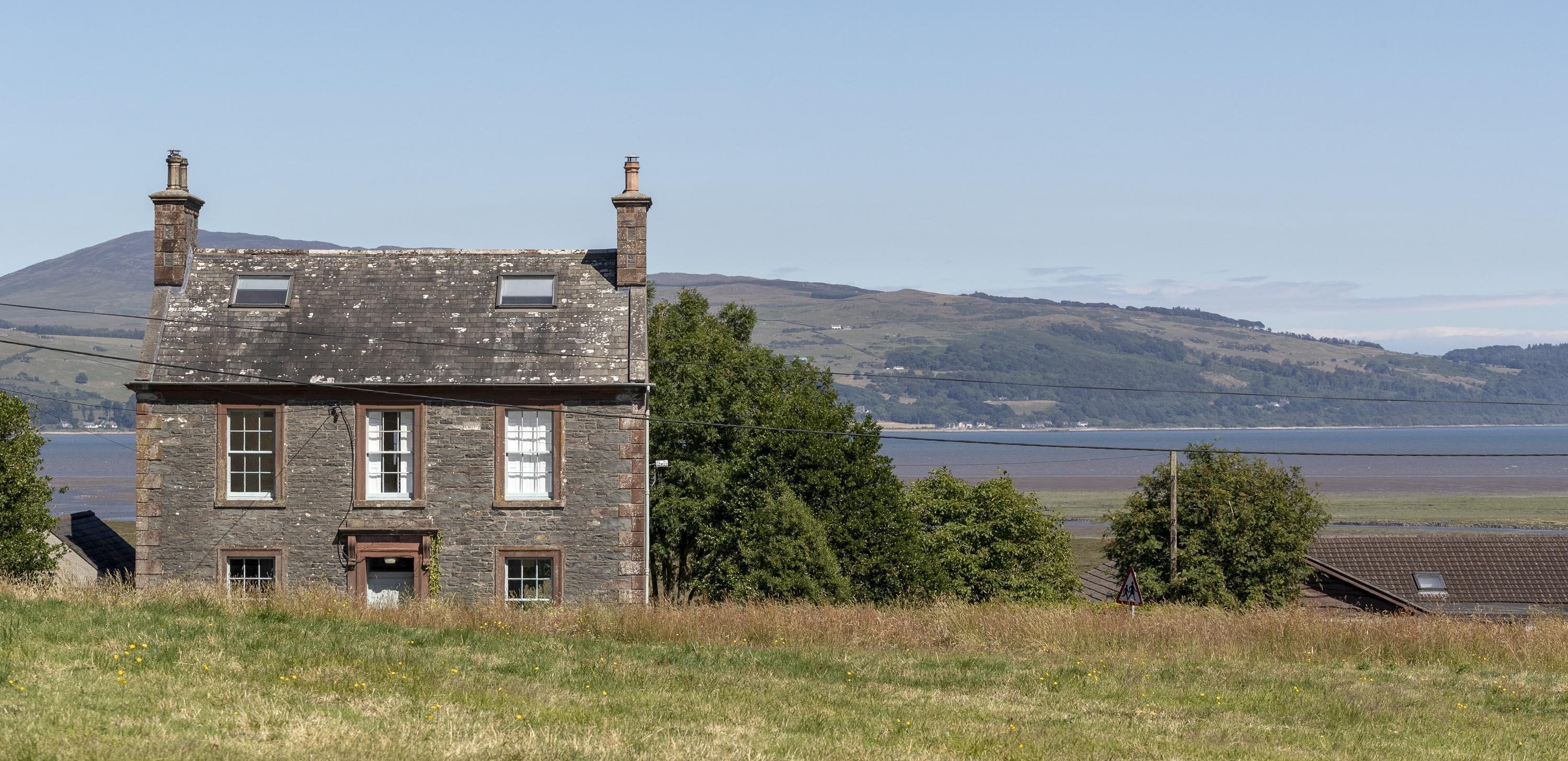 A view of a double fronted old stone house in Wigtown, Scotland's National Book Town. Wigtown bay and the Galloway hills in the distance.