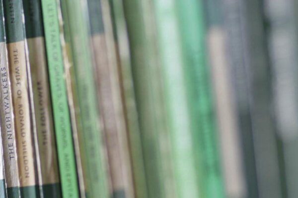 A row of vintage books on a bookshelf in one of Wigtown's second hand bookshops. Most are green and white, a range of penguin and pelican paperbacks.