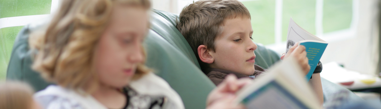 Two young children relaxing on beanbags, reading books at a Children's Book Festival event.