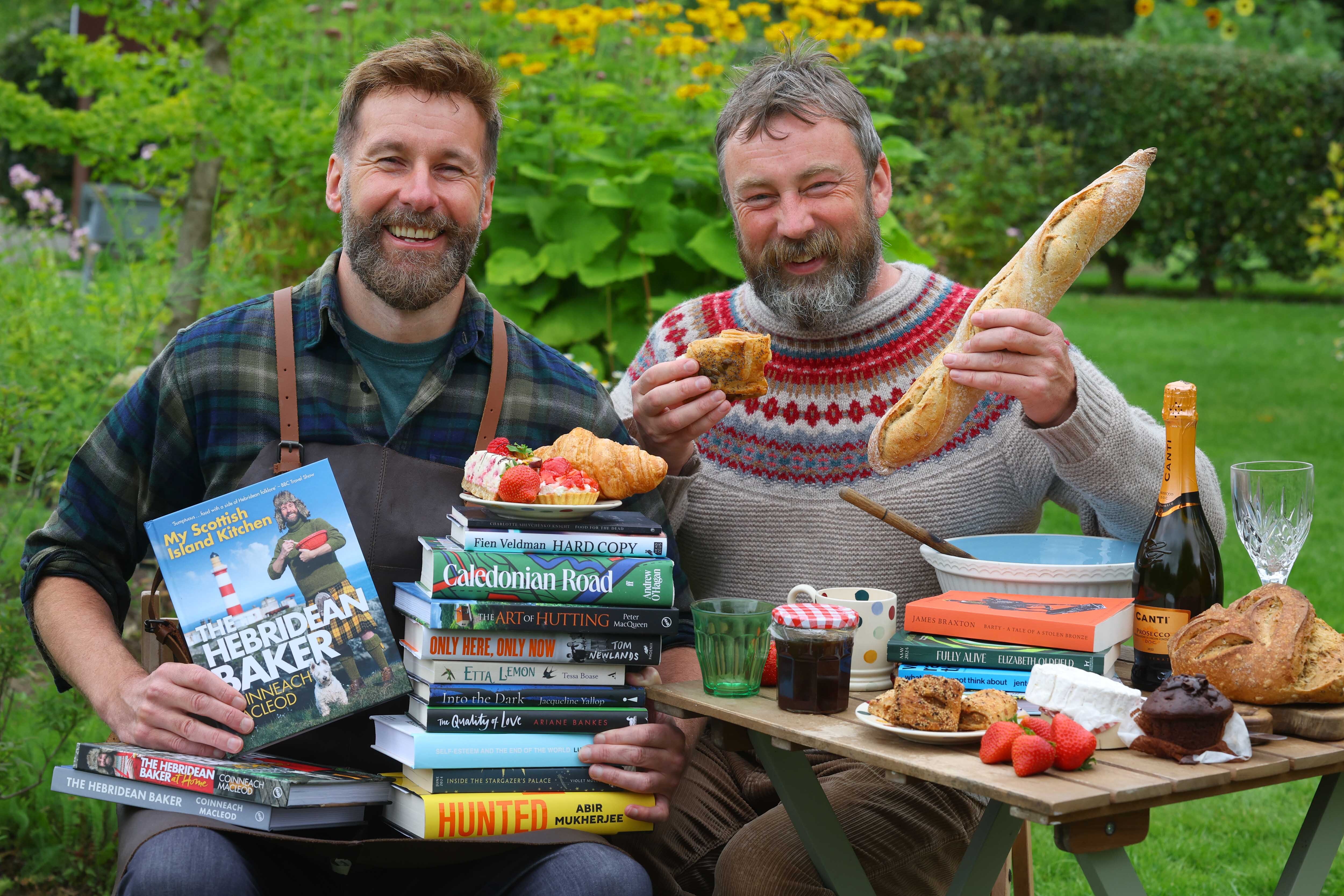 WBF 2024 Programme Launch PR image. Peter MacQueen and Coinneach MacLeod at a picnic with baked goods and books.