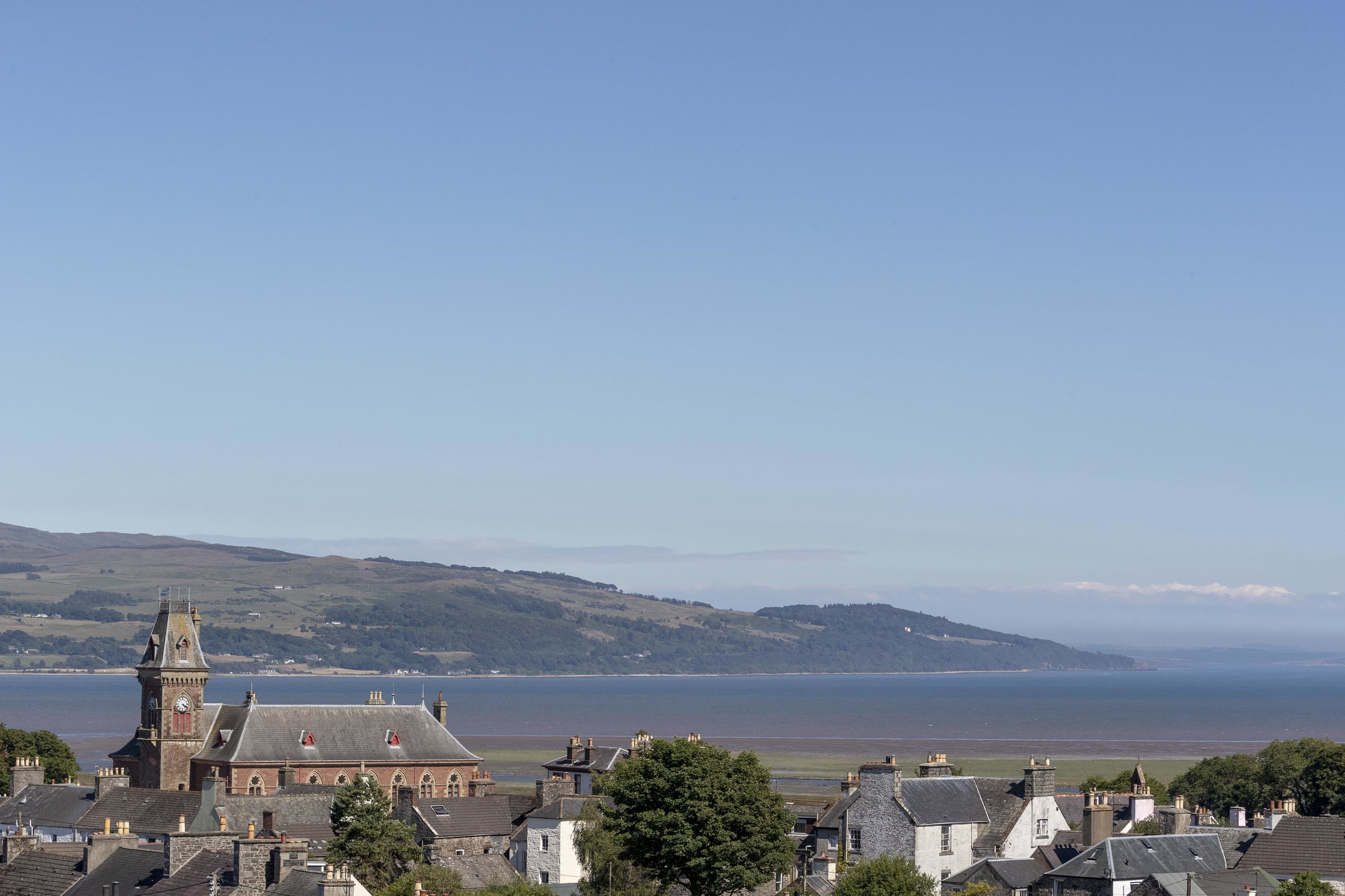 A view over the rooftops of Wigtown towards the Cree estuary and Wigtown Bay. The County Buildings, a red sandstone building with a large clock tower is prominent.