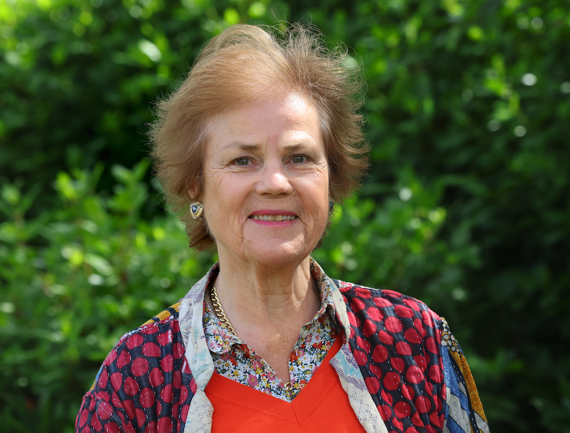 Portrait of Cathy Agnew, Wigtown Book Festival Chair 2025, with sunlit greenery in the background.