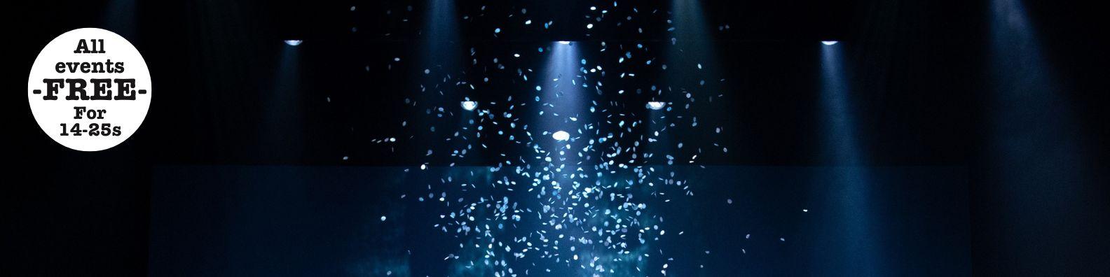 White confetti falling, highlighted by blue lights.