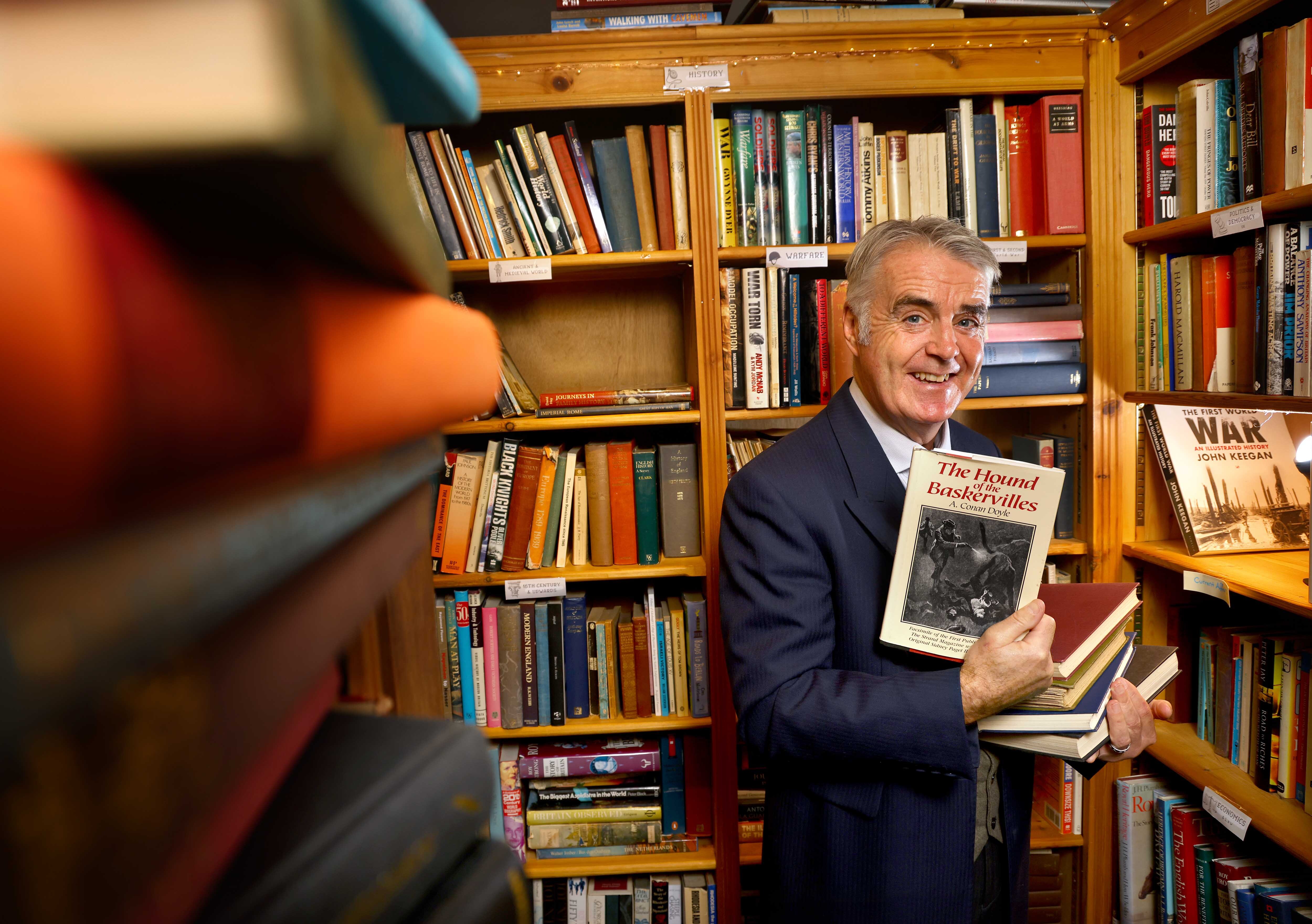 Portrait of Tim Marriott in a bookshop, holding a copy of the Hound of the Baskervilles