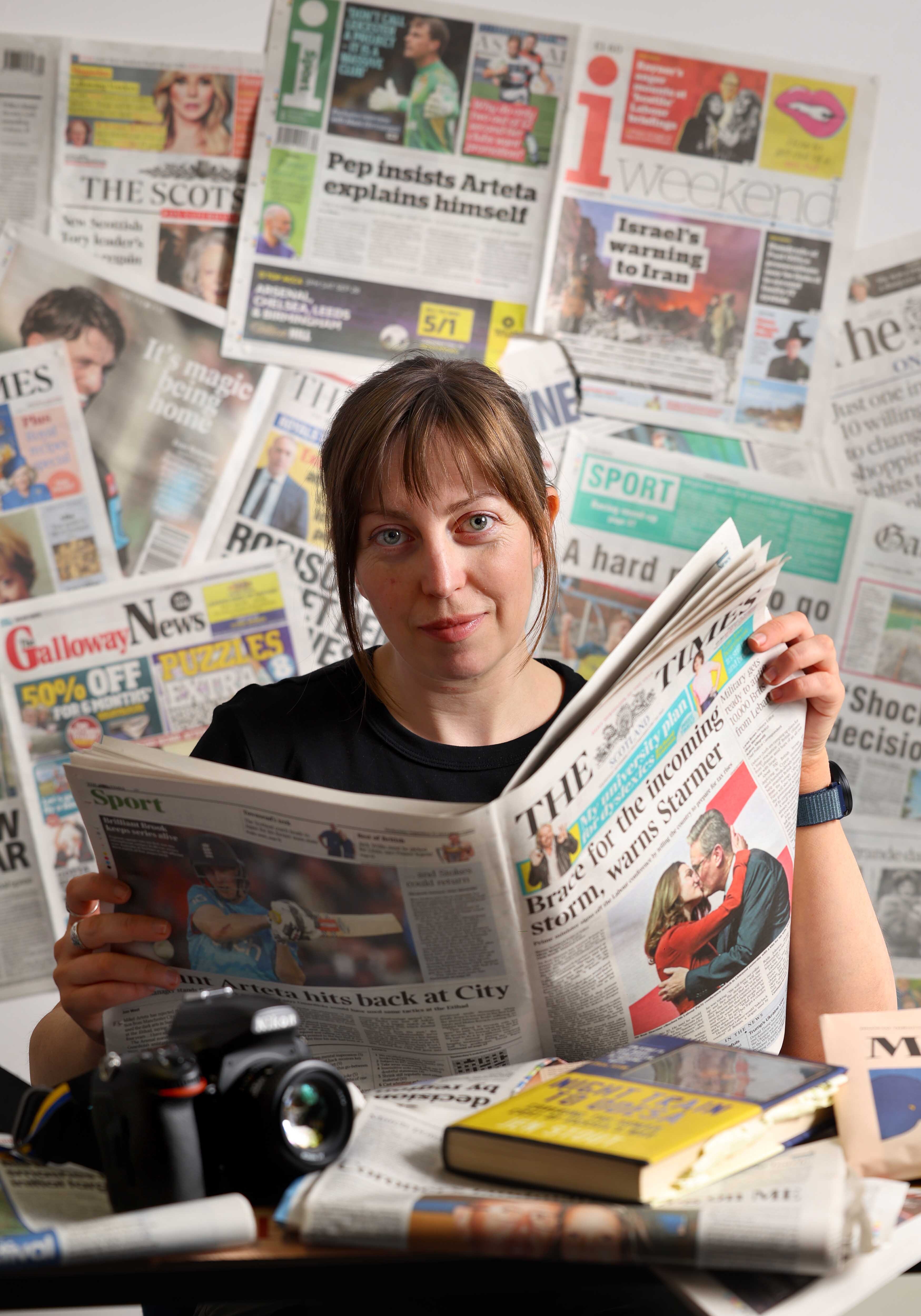 Portrait of Foreign Correspondent Jen Stout surrounded by newspapers