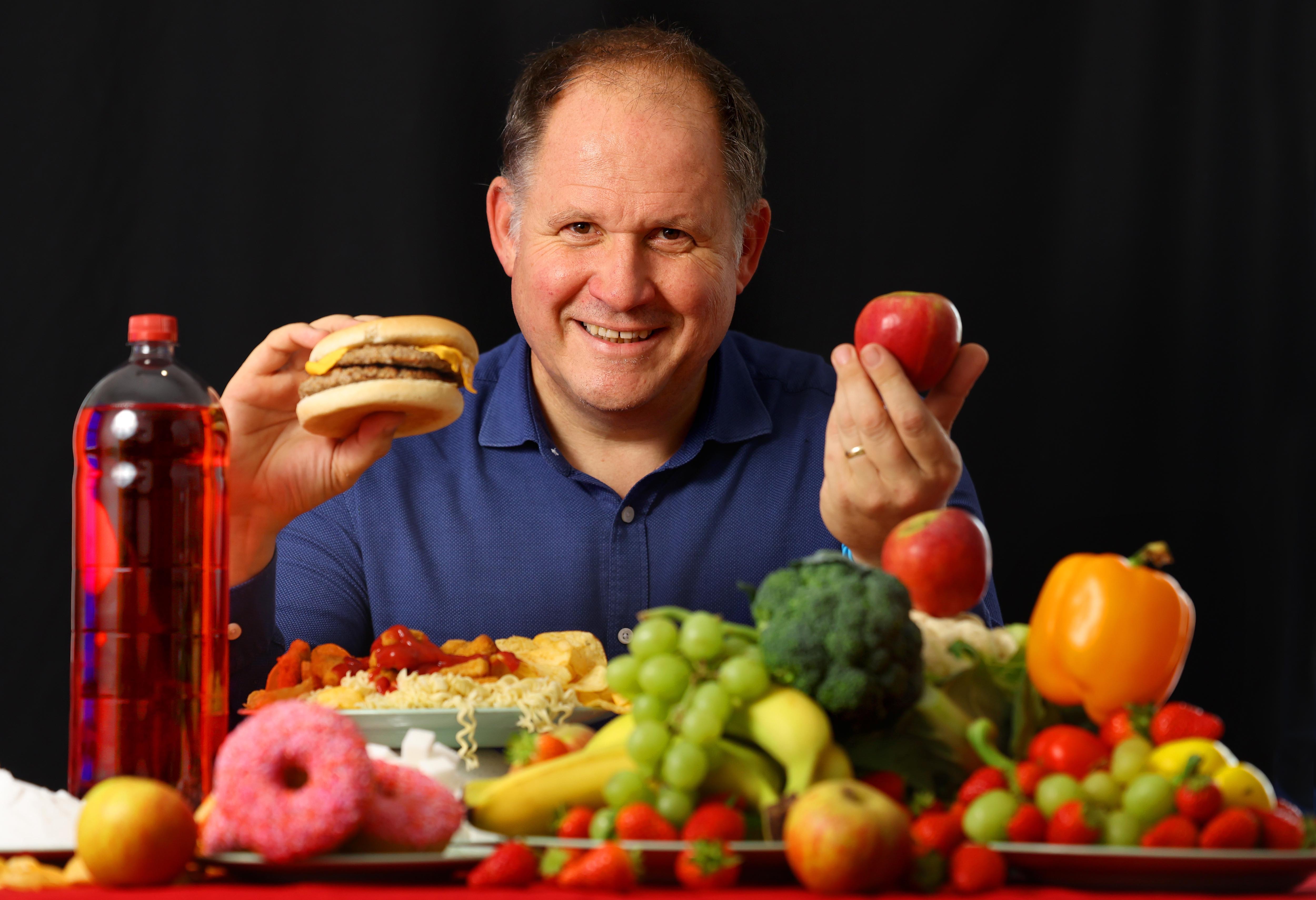 Author Henry Dimbleby seated at a table surrounded by food.