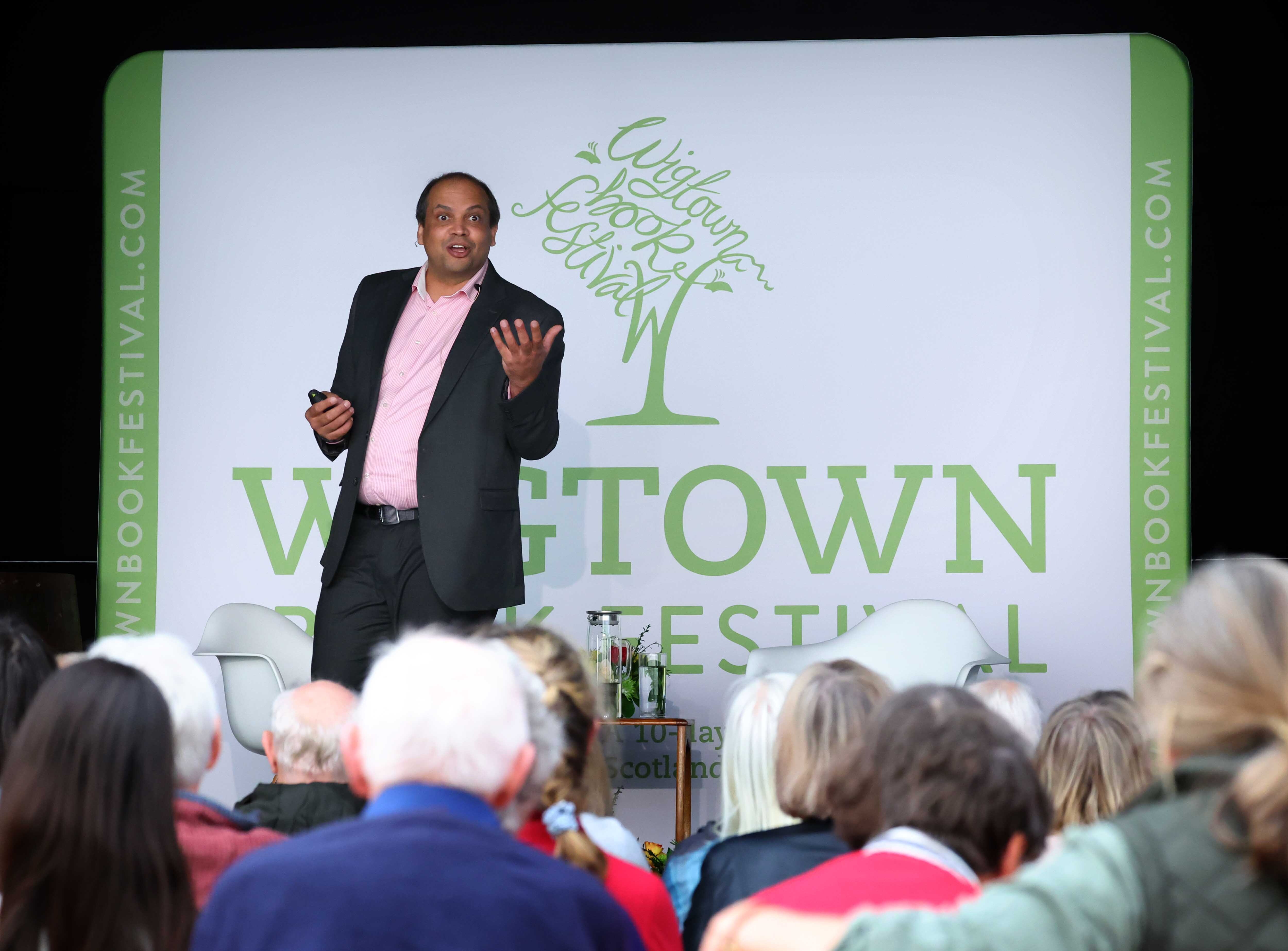 Professor Matthew Agarwala at his event in Wigtown, on stage in front of a Wigtown Book Festival banner