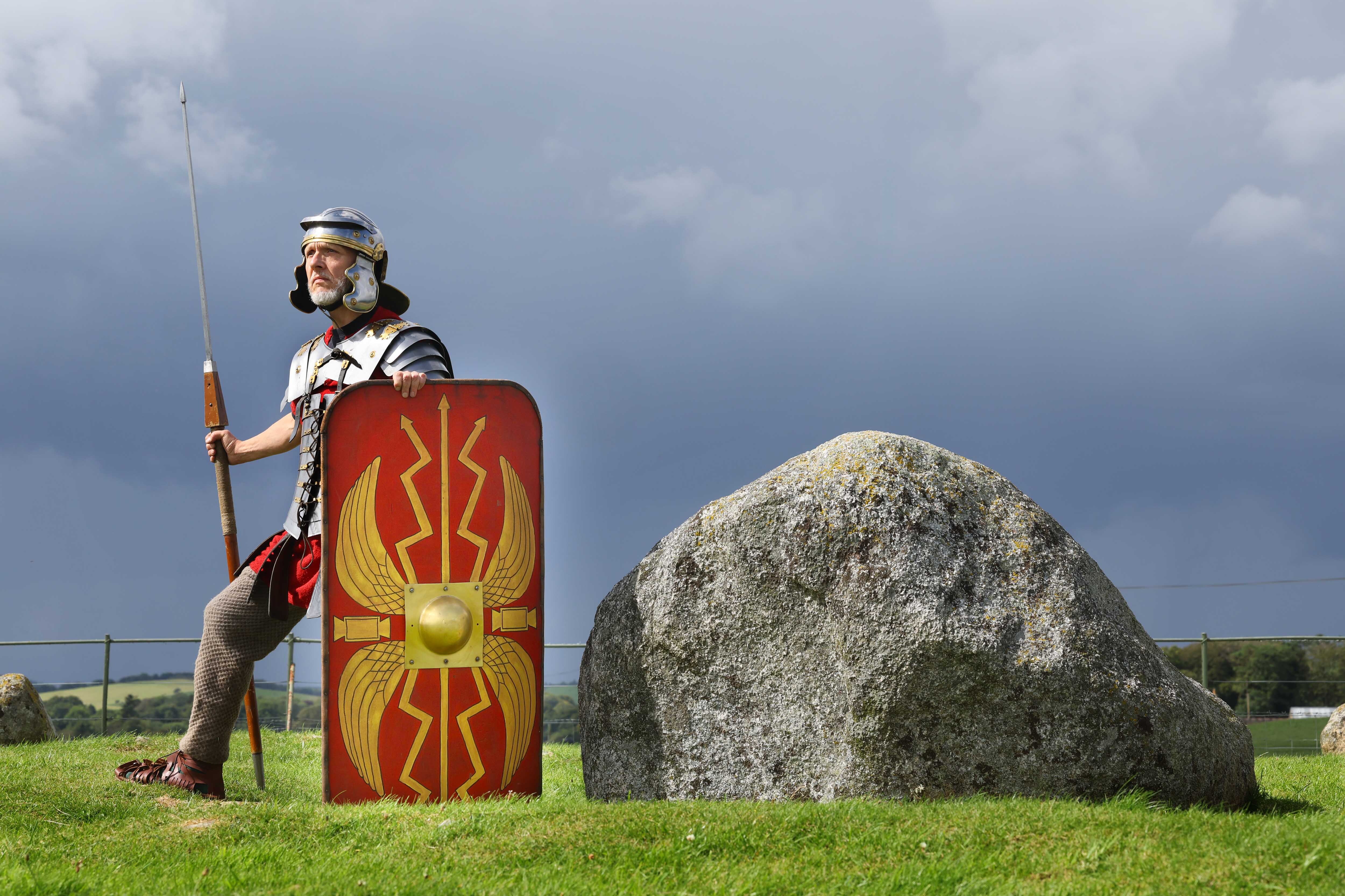 Matthew Shelley dressed as a Roman centurion, stood next to a boulder on a hill, looking noble