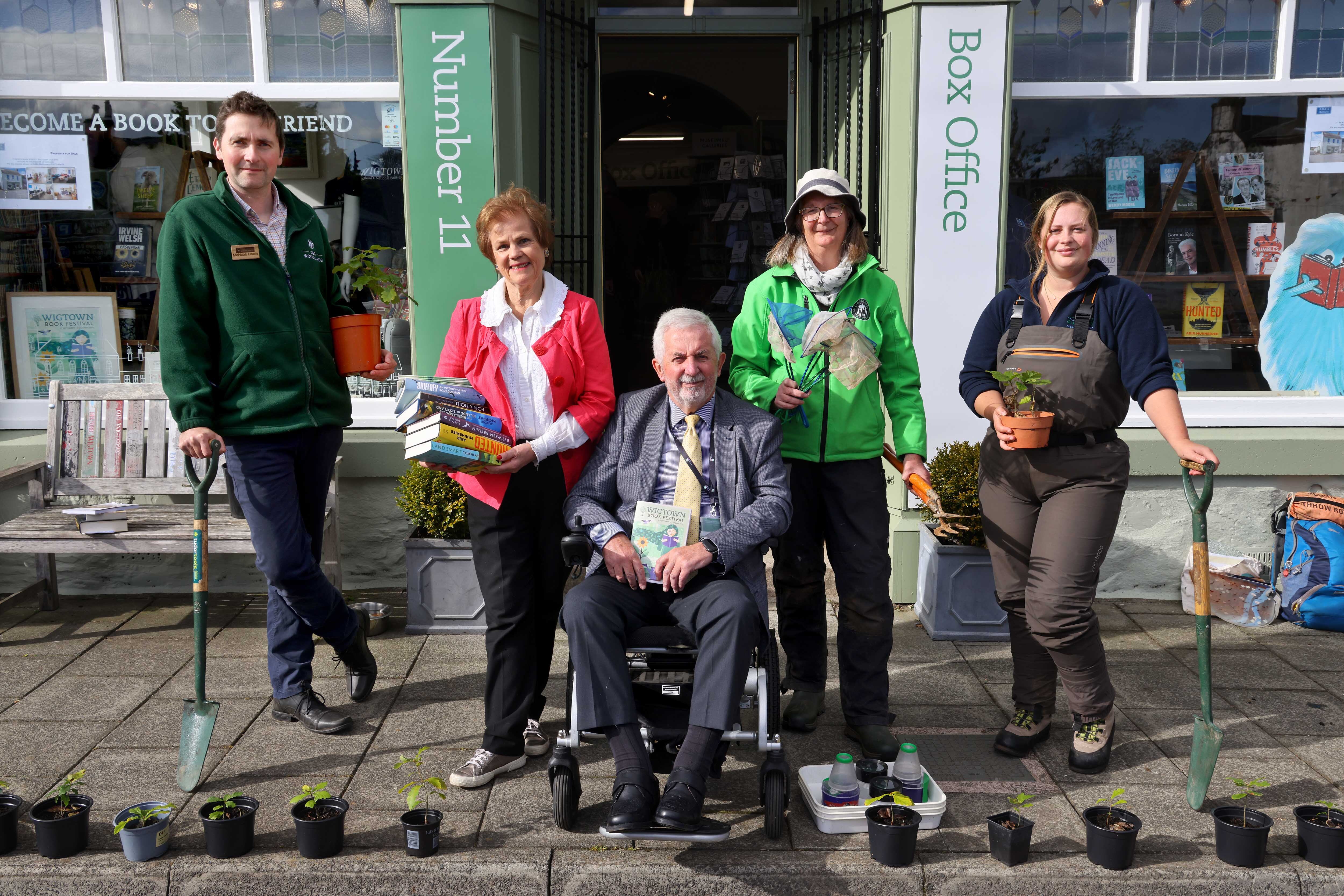 Coastal fringe event guides and company chair Cathy Agnew holding books and potted plants outside Number 11 Bookshop