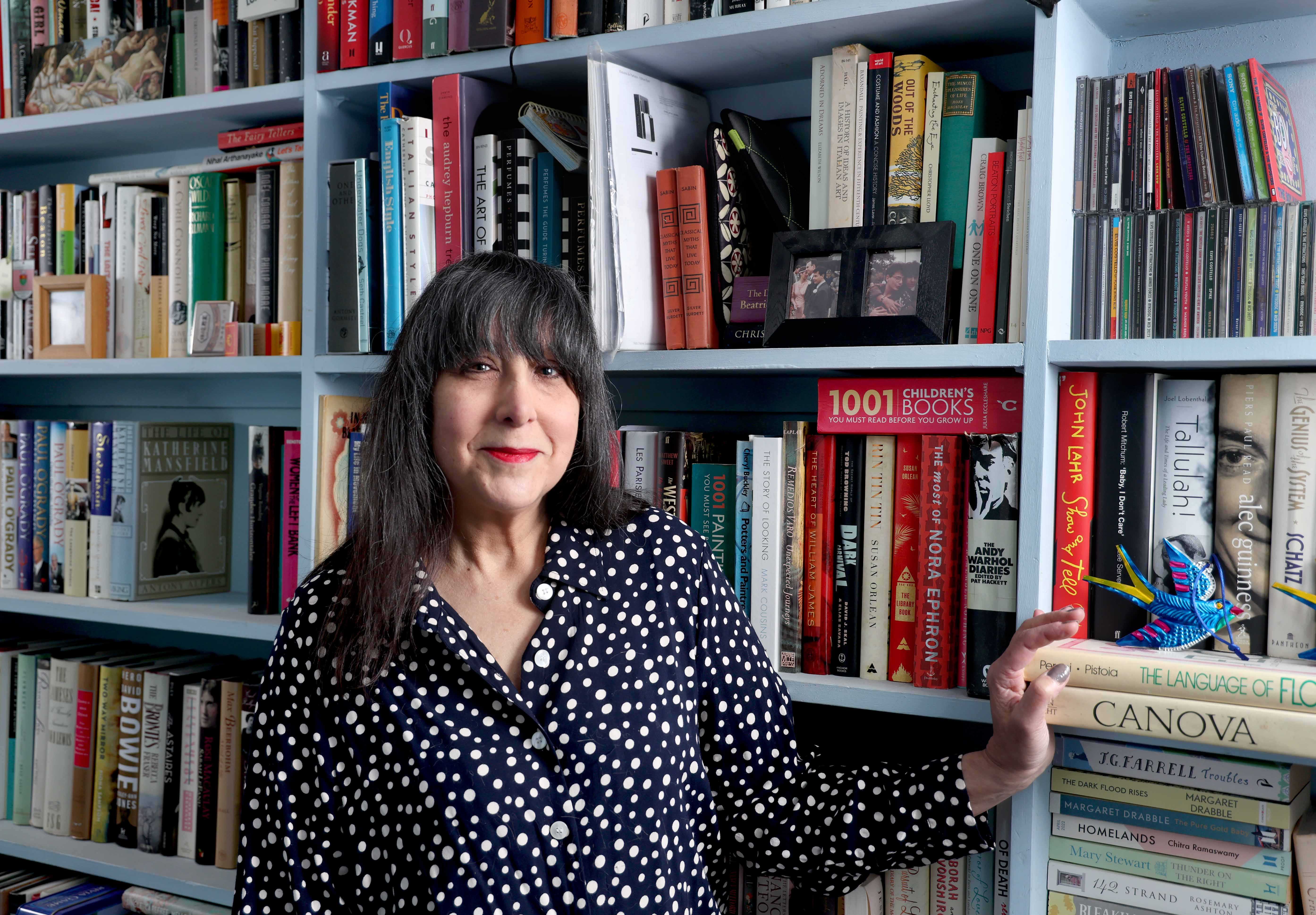 Lee Randall standing in a bookshop. The bookshelves behind her are full of books.