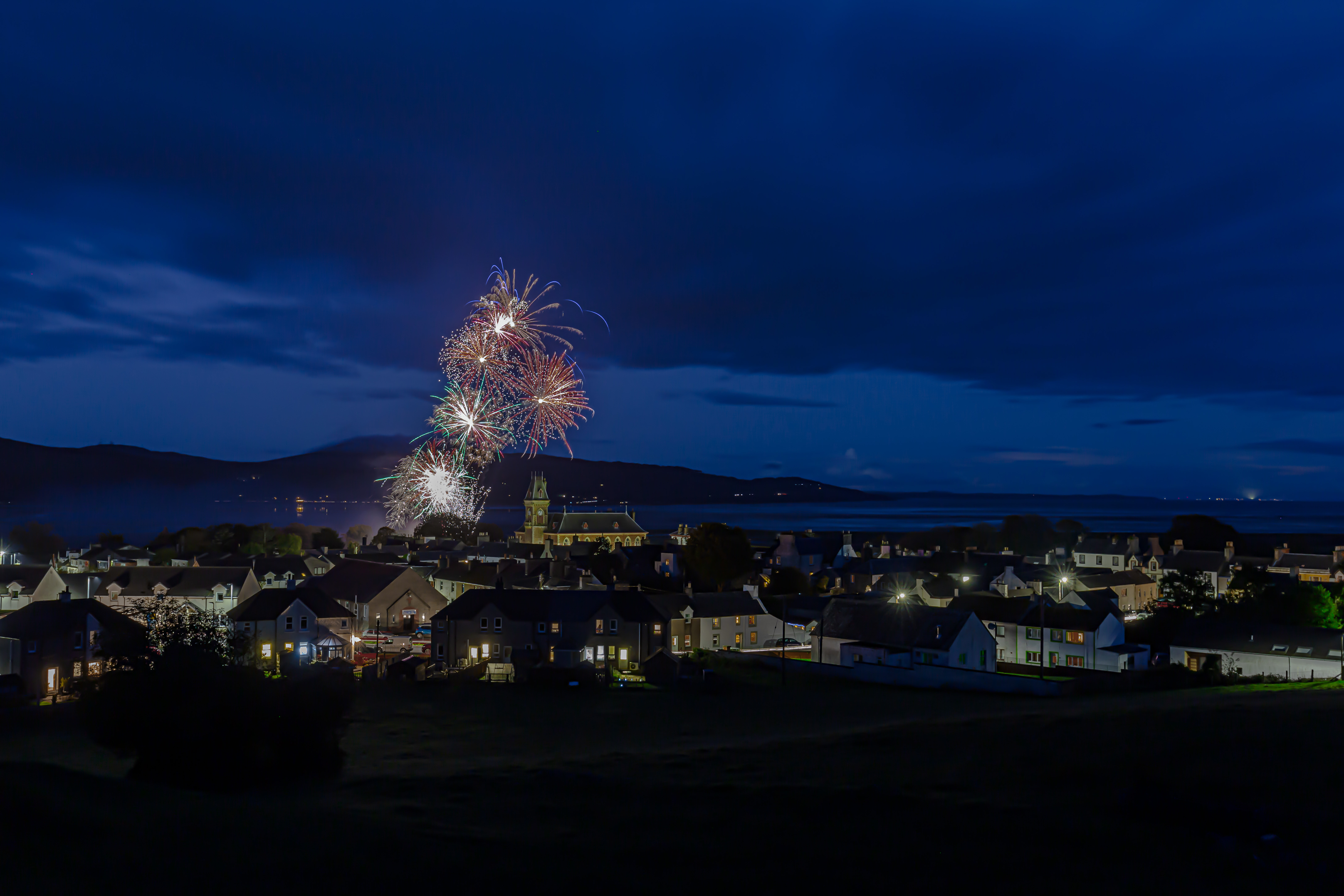 Aerial view  of Wigtown, fireworks are exploding in the sky above the County Buildings to celebrate the opening of Wigtown Book Festival.