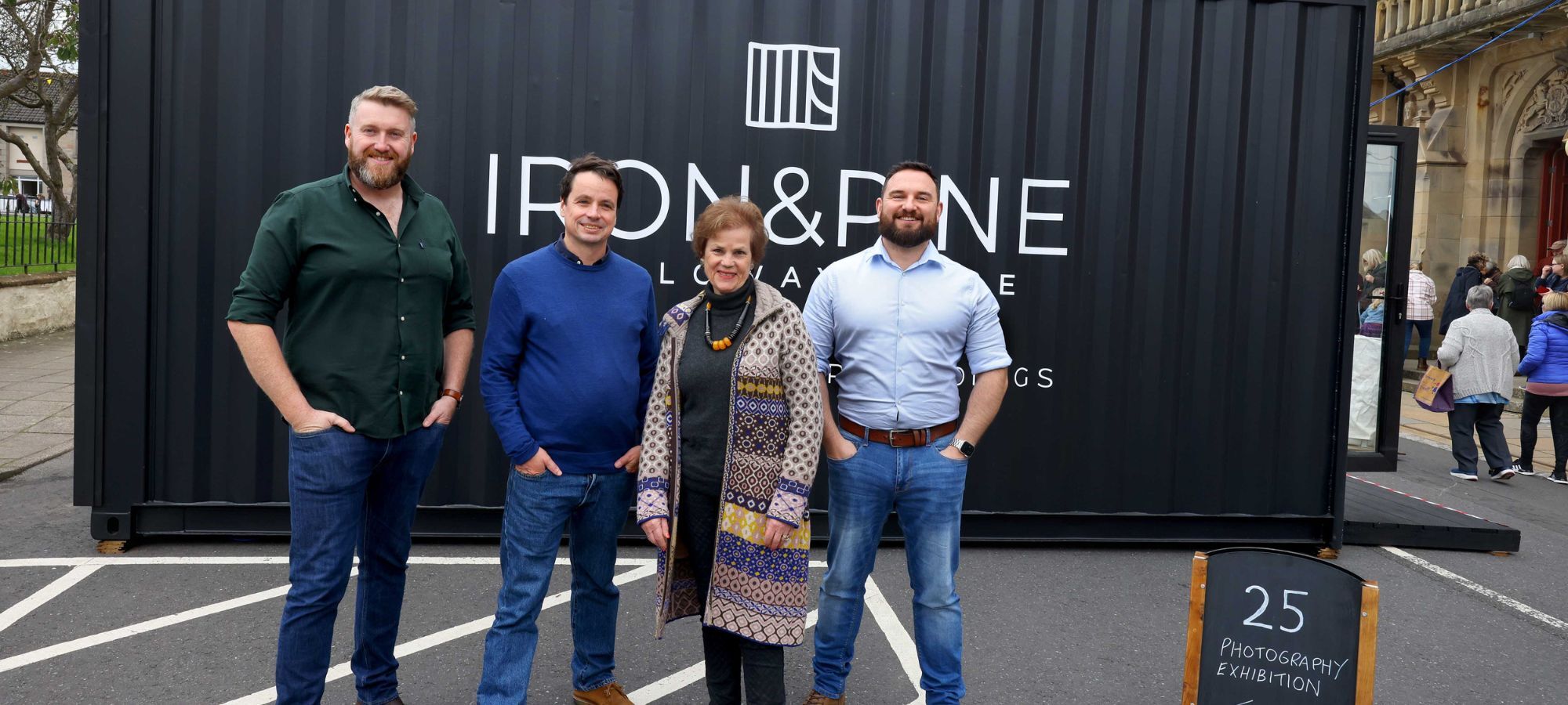 Two Iron and Pine executives, festival Director Adrian Turpin and Festival Chair Cath Agnew stand in front of Iron and Pine exhibition space for the 25th Wigtown Book Festival.