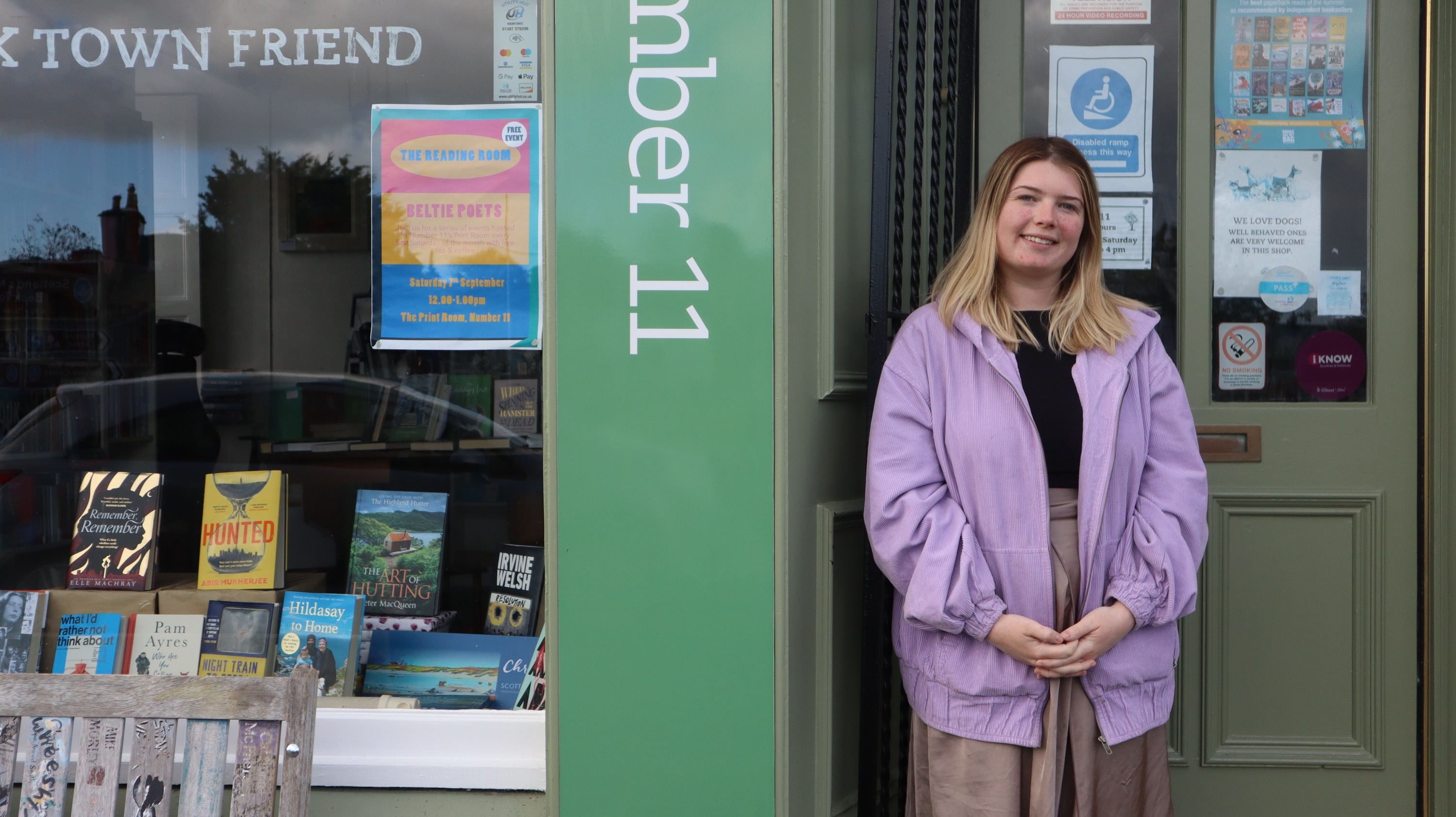 Youth Engagement Officer Morgan Love stood in front of Number 11 Bookshop, leaning against doorpost, mid-shot.