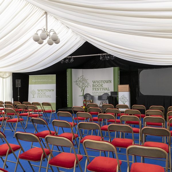 Inside an empty marquee at Wigtown Book Festival. Rows of chairs and the stage ready for an event.