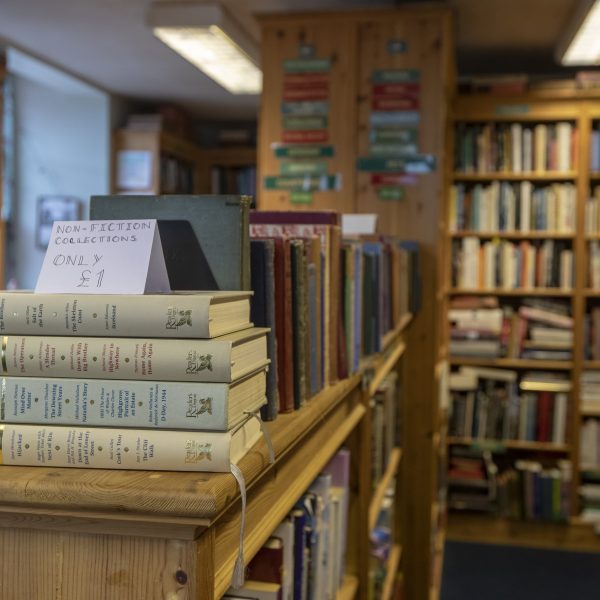 Bookshelves full of books inside The Open Book bookshop. Stacked books in the forefront for sale at £1.