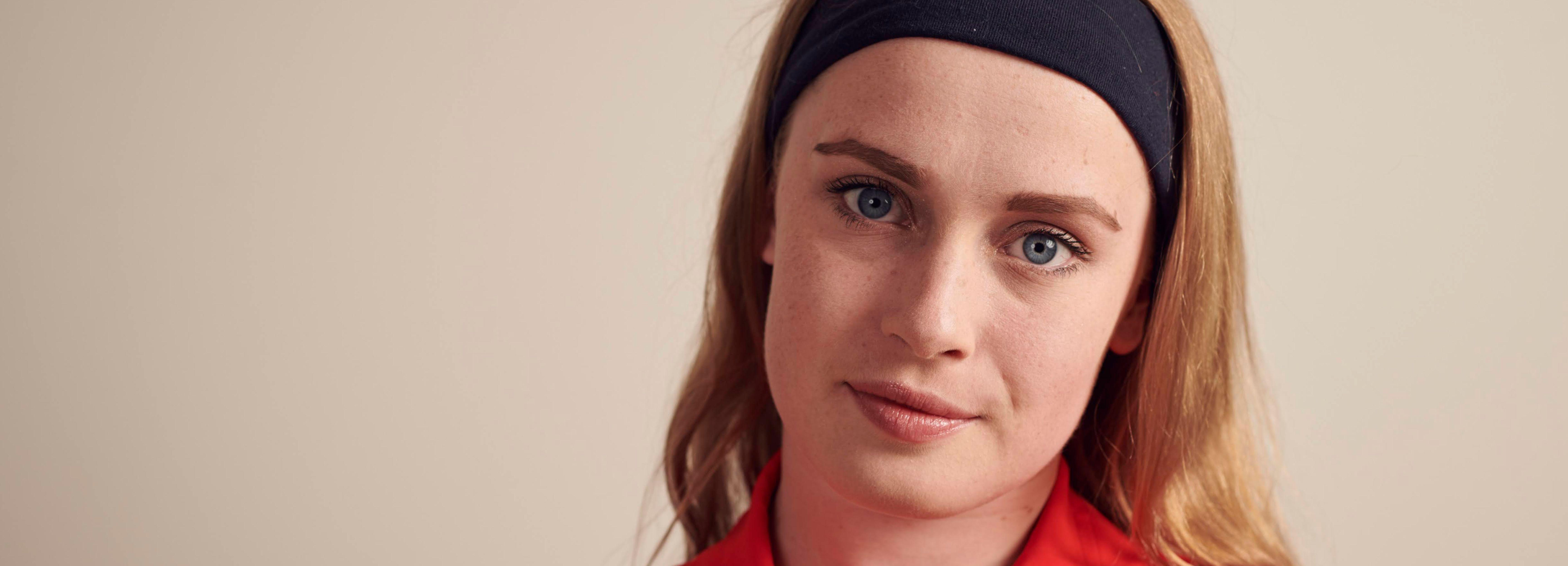 Headshot of Ellie Robinson. She is wearing a red t-shirt and a black band in her hair.