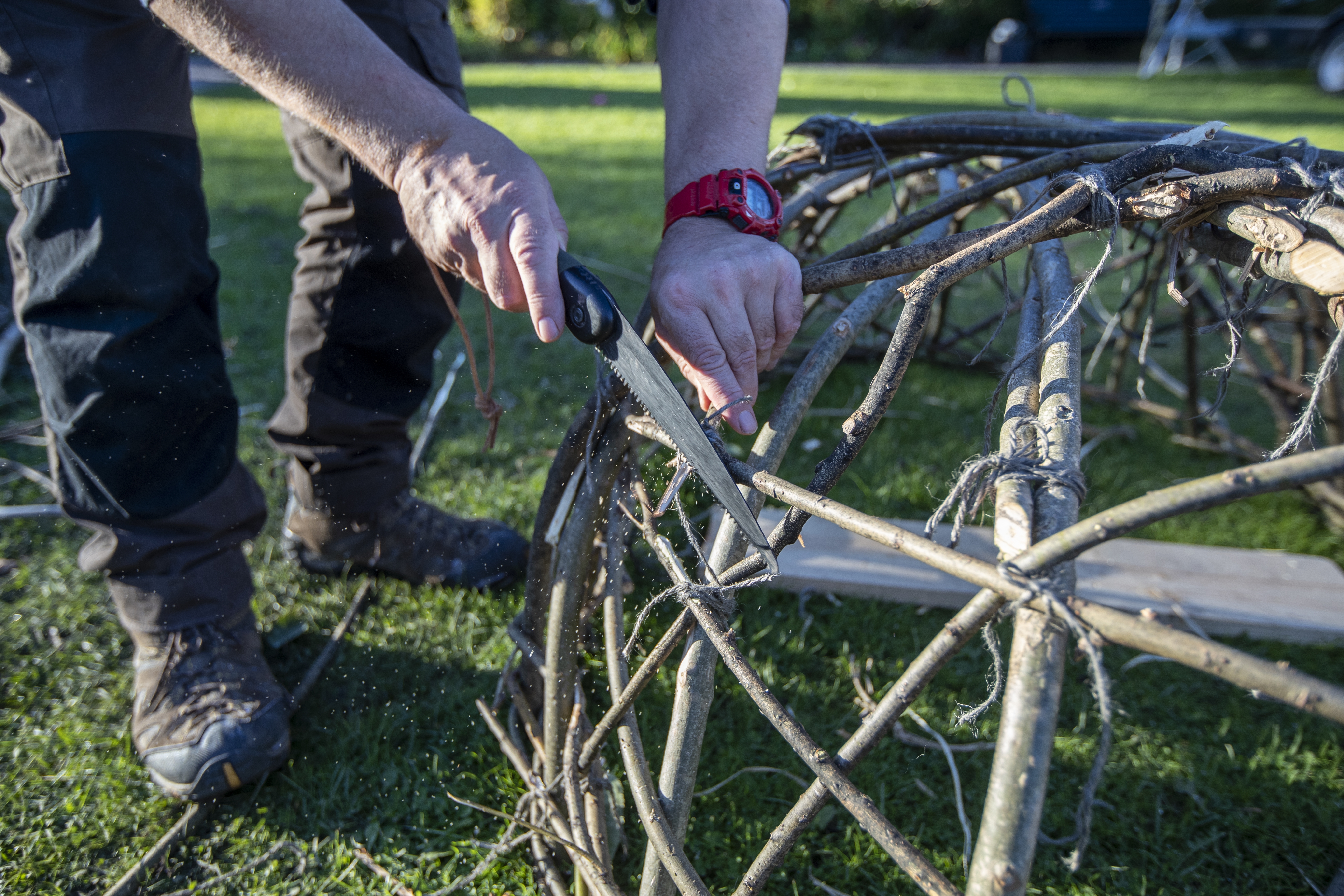 Robert Twigger is hand crafting a coracle. A small wood woven boat. In his hands he holds a small saw.