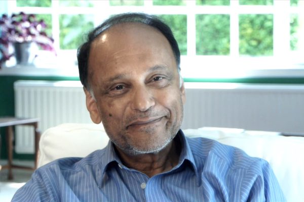 Headshot of Sir Partha Dasgupta, sitting in a sun filled room.