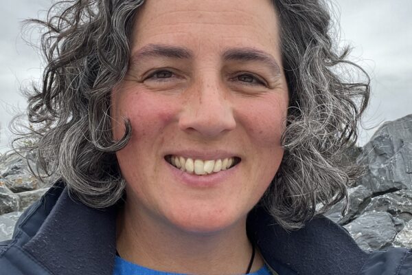 Headshot of Isla Rosser-Owen outside by coastal rocks