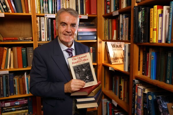 Portrait of Tim Marriott in a bookshop, holding a copy of the Hound of the Baskervilles