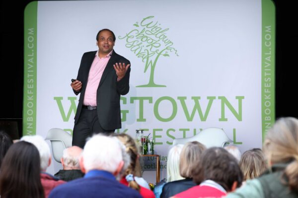 Professor Matthew Agarwala at his event in Wigtown, on stage in front of a Wigtown Book Festival banner