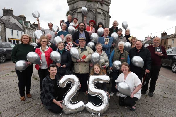 Wigtown Bookshop owners along with staff and volunteers from Wigtown Festival Company, are gathered at Mercat Cross holding silver balloons to celebrate twenty five years of Wigtown Book Festival.