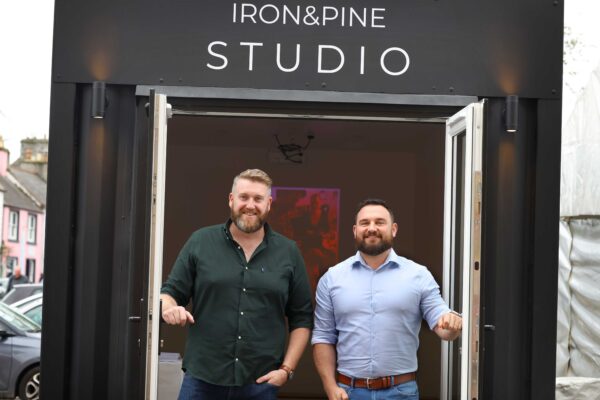 Two Iron and Pine executives stood outside the 25th festival photo exhibition, created from a shipping container.