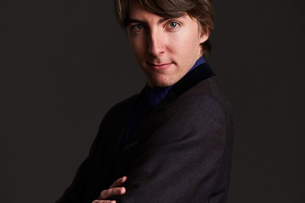 Headshot of children's author Jack Meggitt-Phillips. He stands smiling with his arms folded.