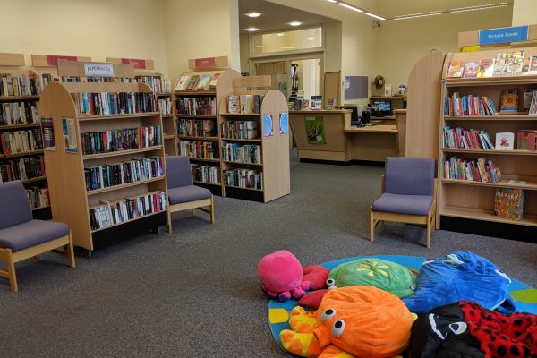 Wigtown library's children section. Lots of bookshelves filled with books, comfortable cosy beanbags on the floor.