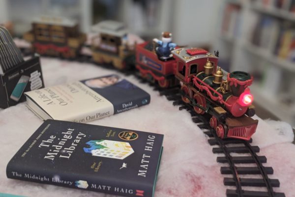 A toy train runs around a track on a table surrounded by books in the Festival Book Shop.
