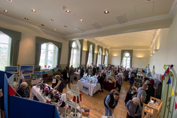 The Spring Kist held in the main hall of Wigtown County Buildings. Stall holders are set up in the main hall, many people are wandering around browsing and buying.
