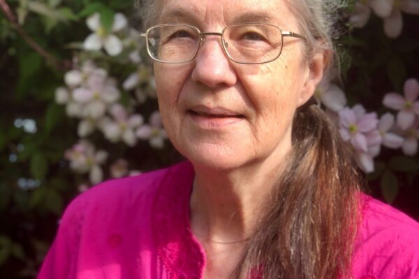 Author and poet Stephanie Green in front of pink flowering bush.