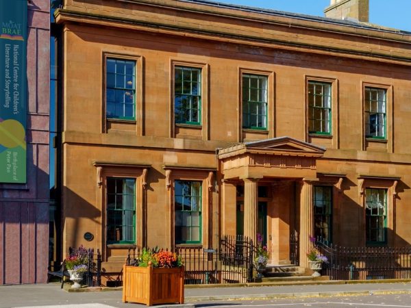 Moat Brae House, Scotland's Centre for Children's Literature and home of J.M. Barrie. A large sandstone house with imposing doorway surrounded by trees.
