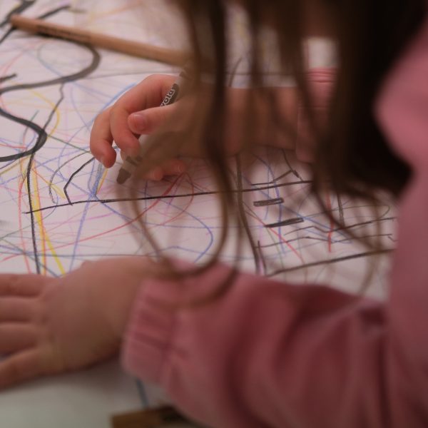 A child is sitting drawing at a desk with black crayons for a Children's Book Festival event.