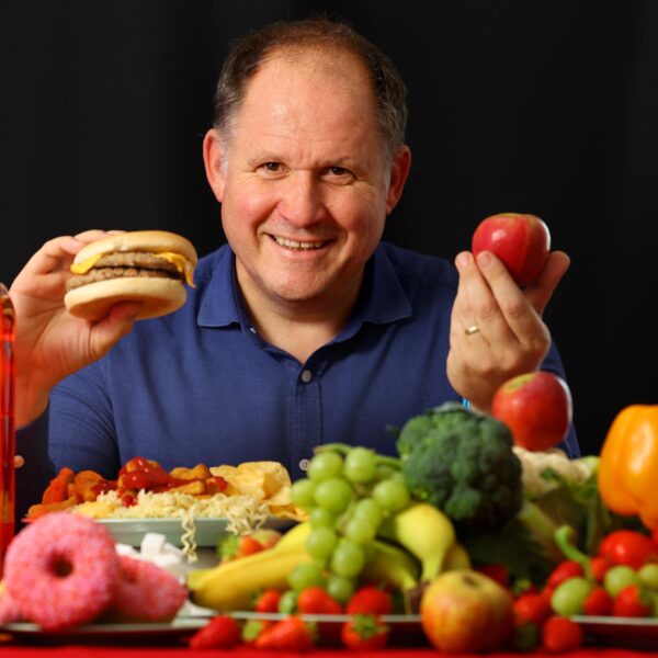 Author Henry Dimbleby seated at a table surrounded by food.