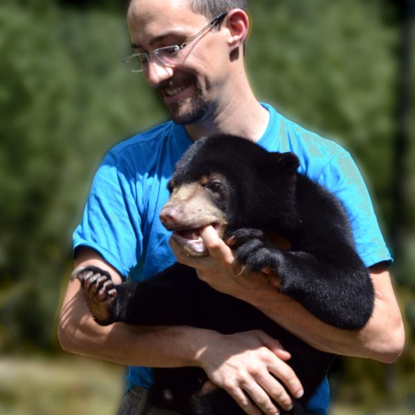 Dr Romain Pizzi is holding a sun bear cub in Cambodia.