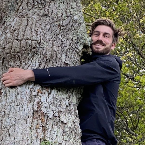Leif bersweden is hugging a tree and smiling.